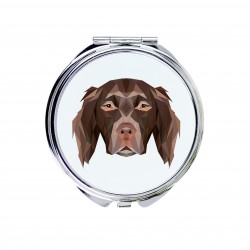 Un espejo de bolsillo con un perro Münsterländer pequeño. Una nueva colección con el perro geométrico